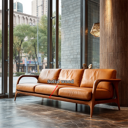 Modern minimalist sofa with curved wood arms and smooth leather cushions placed beside large glass windows