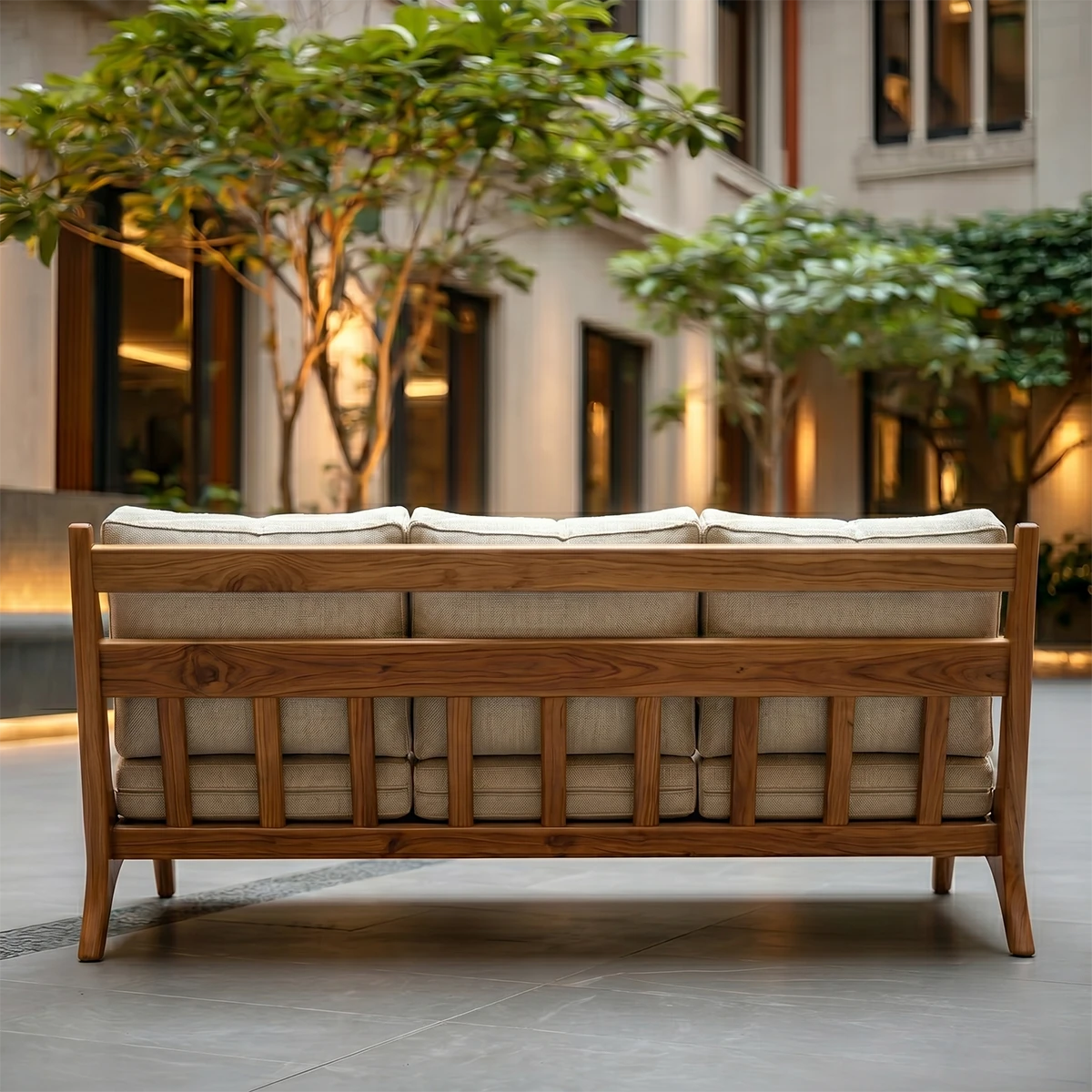 Elegant modern couch with beige upholstery and curved wooden frame placed in serene courtyard