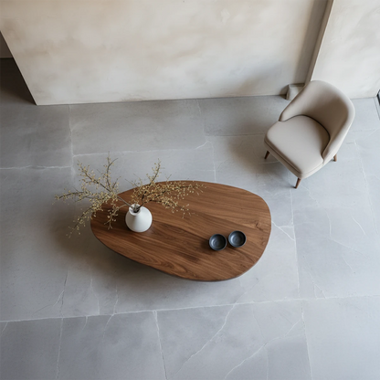 Walnut coffee table with artistic sculptural base and natural flowing shape placed in minimalist interior setting