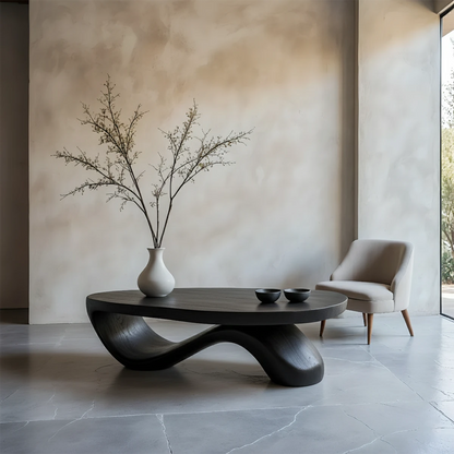 Minimal black coffee table with fluid curved base and solid top design in a clean modern living space