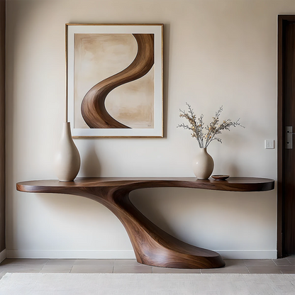 Sculptural console table in solid wood with flowing curves, styled in a modern minimalist entryway
